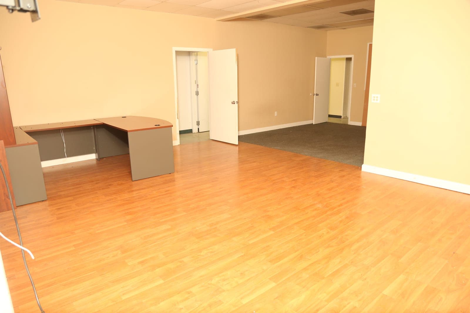 Interior office rooms with wood-look flooring and carpeted rear section at 1883