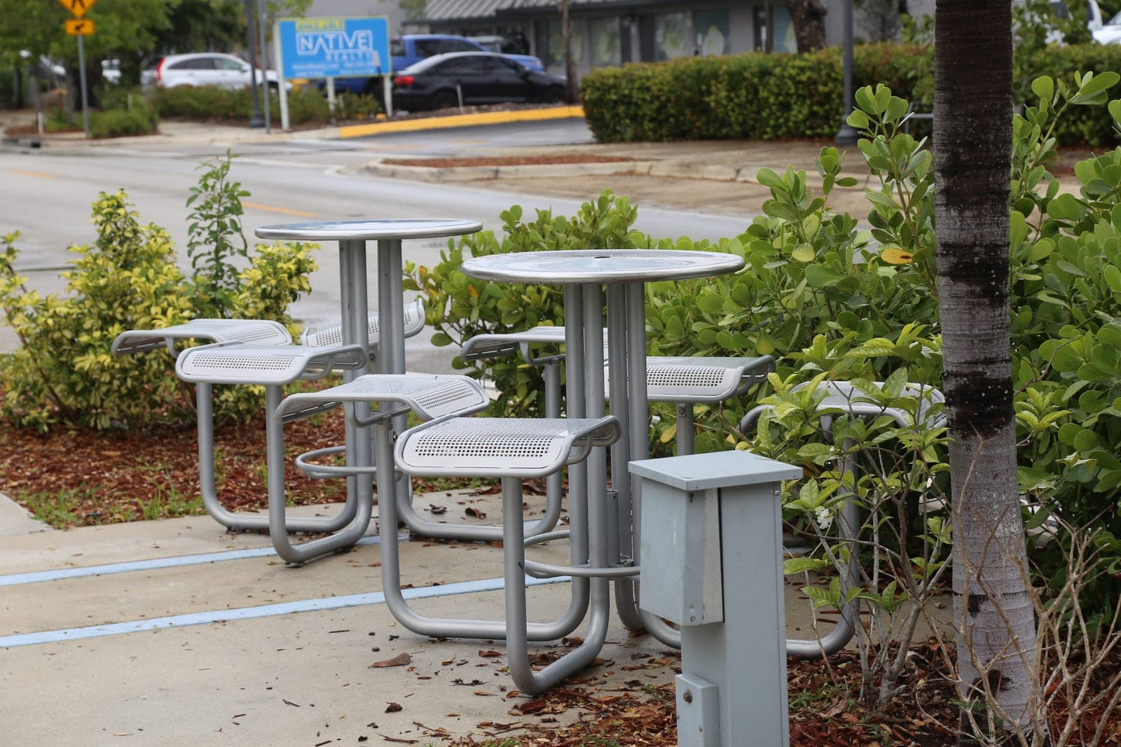 Round perforated metal tables with attached seats next to the kiosks