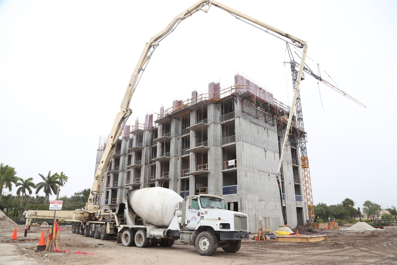 Concrete mixer, boom pump, and multi-story building under construction at Le Parc